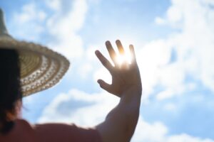 Persona si protegge dal sole con la mano