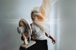 Uomo con il ventilatore puntato in viso e una tenda avvolta intorno alla testa