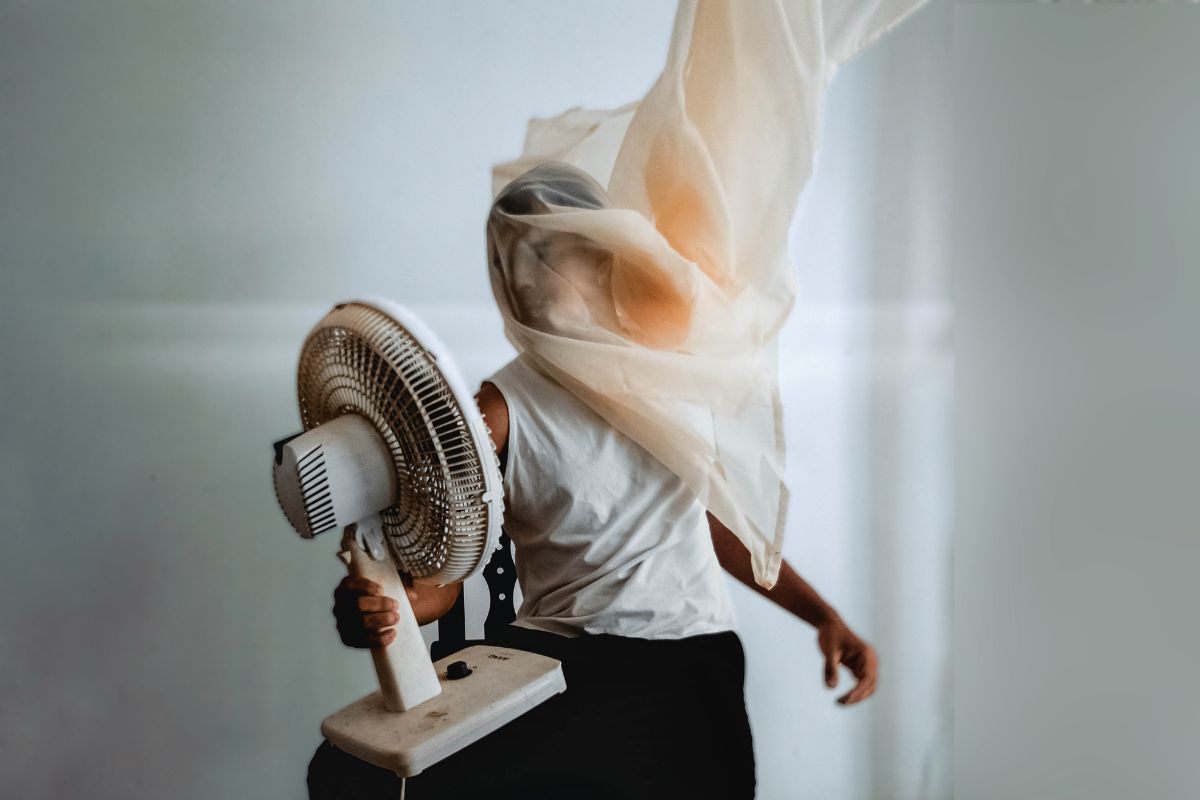 Uomo con il ventilatore puntato in viso e una tenda avvolta intorno alla testa