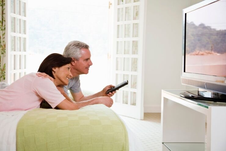 Coppia sul letto guarda TV