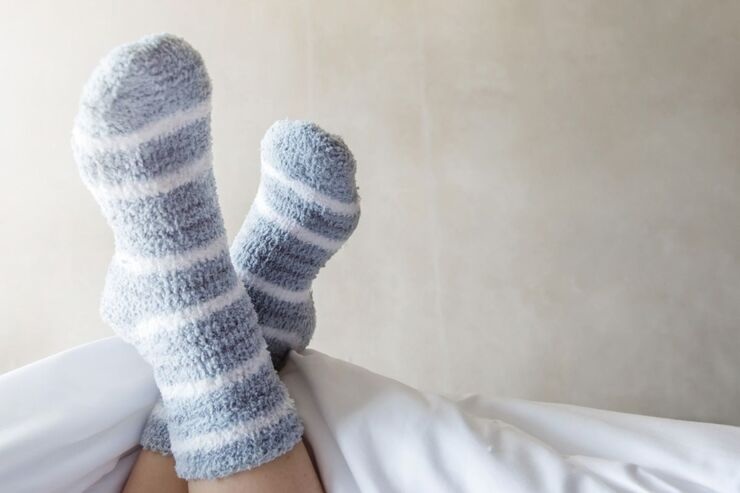 Piedi sollevati e incrociati sul letto con i calzini 