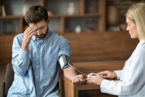 Uomo con mano sulla fronte che si fa misurare la pressione