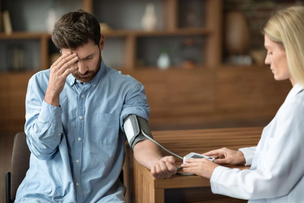 Uomo con mano sulla fronte che si fa misurare la pressione