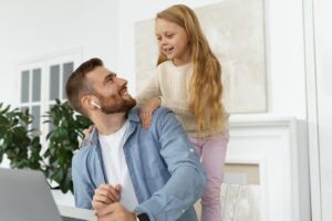 Papà al computer che guarda la figlia piccola