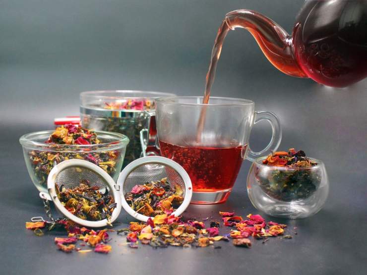 teiera versa tisana in tazza e erbe varie