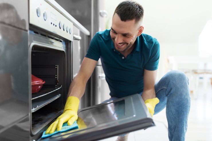 uomo che pulisce forno