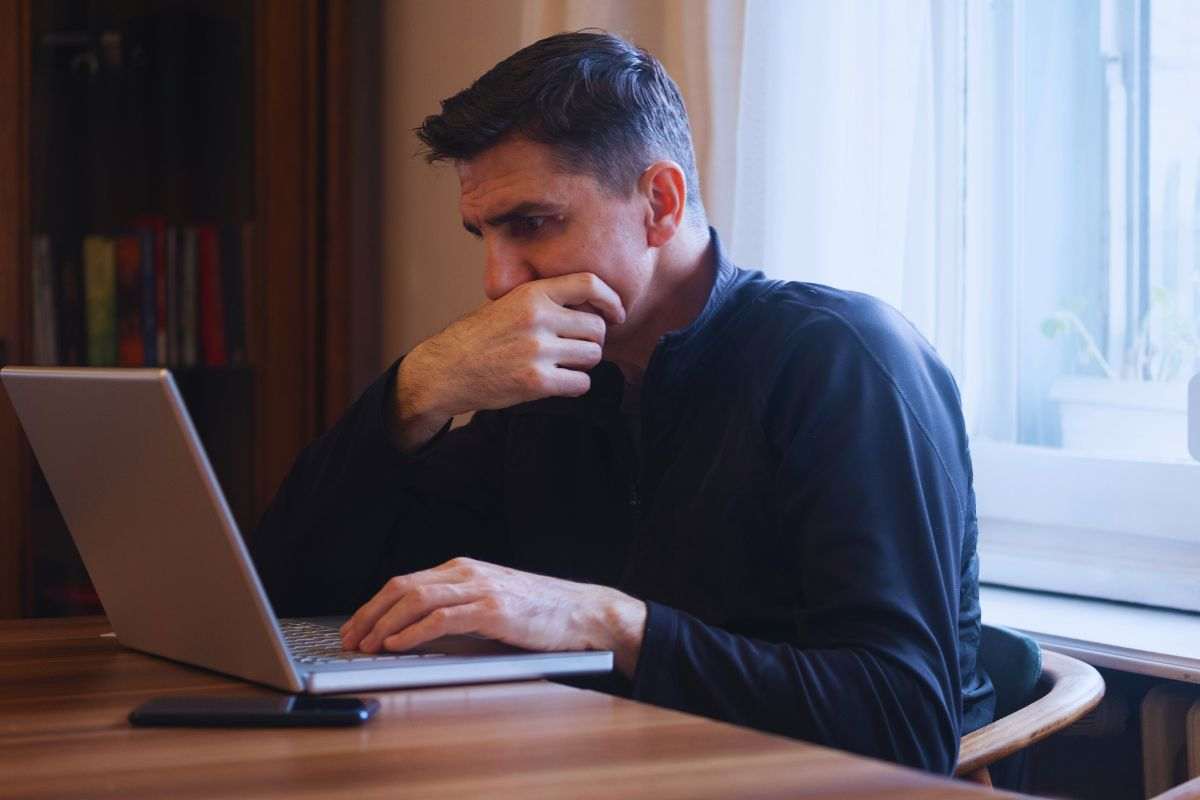Uomo preoccupato mentre utilizza portatile