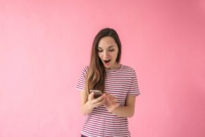 donna con espressione stupita con il cellulare in mano