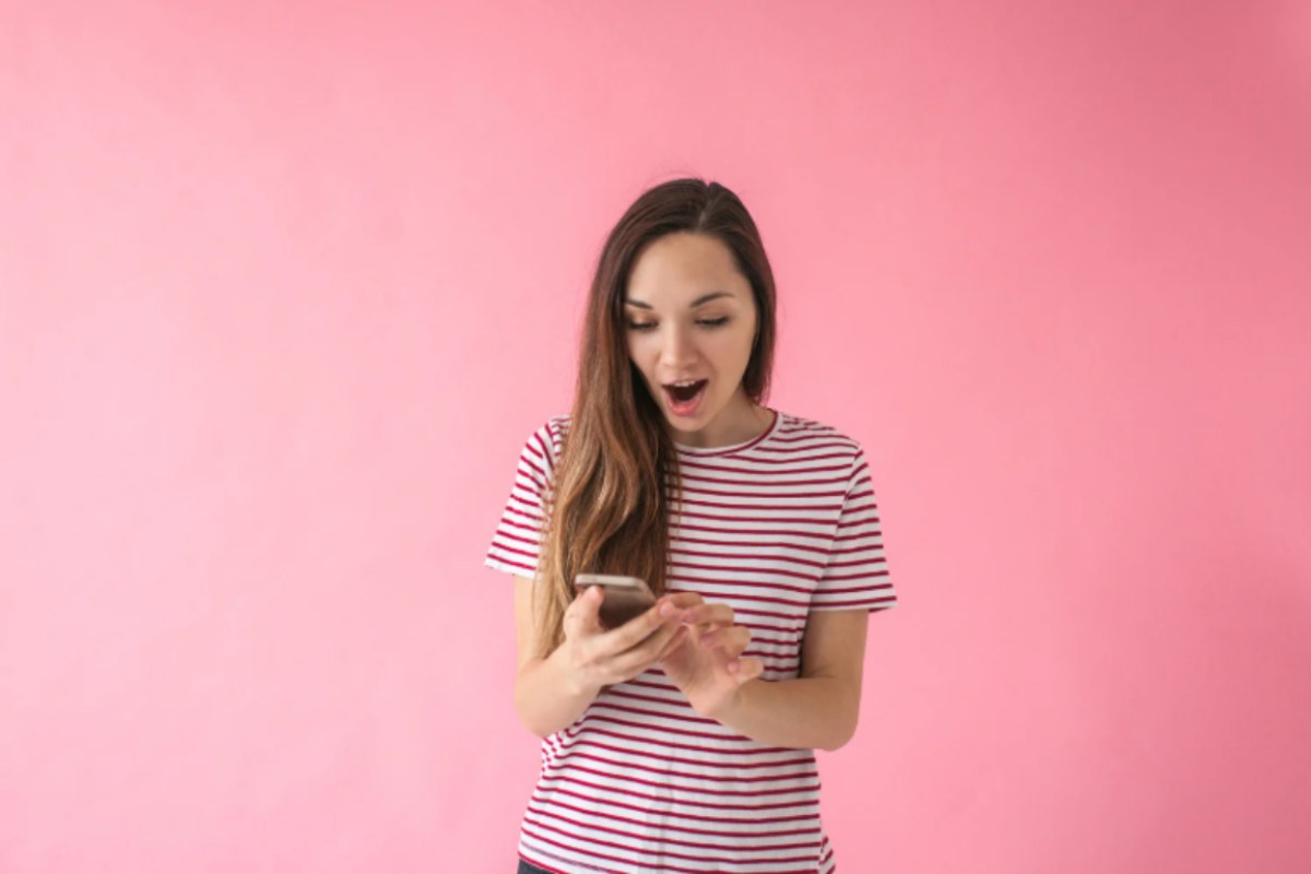 donna con espressione stupita con il cellulare in mano