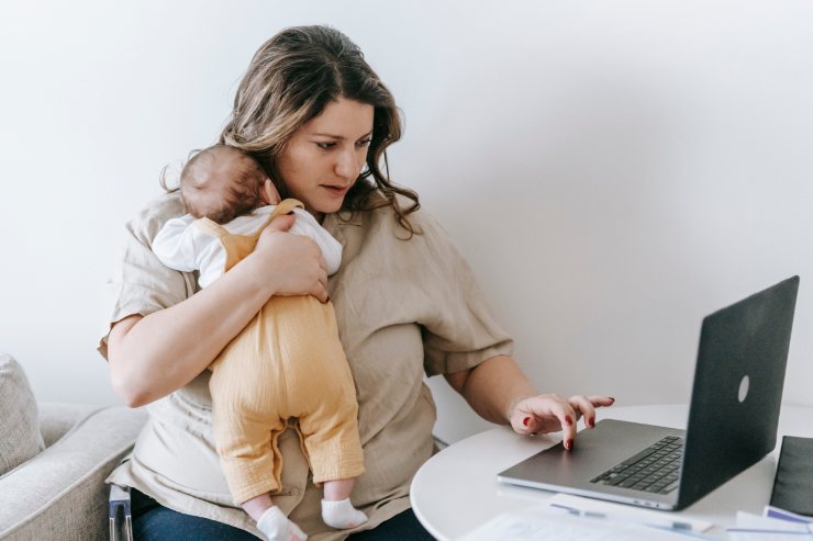 donna lavora con figlio piccolo in braccio