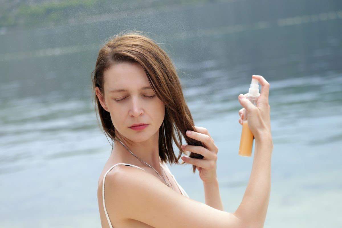 Donna che spruzza spray su capelli