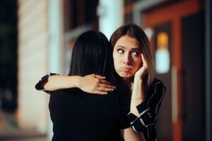Donna abbraccia un'altra donna ma appare un po' scocciata
