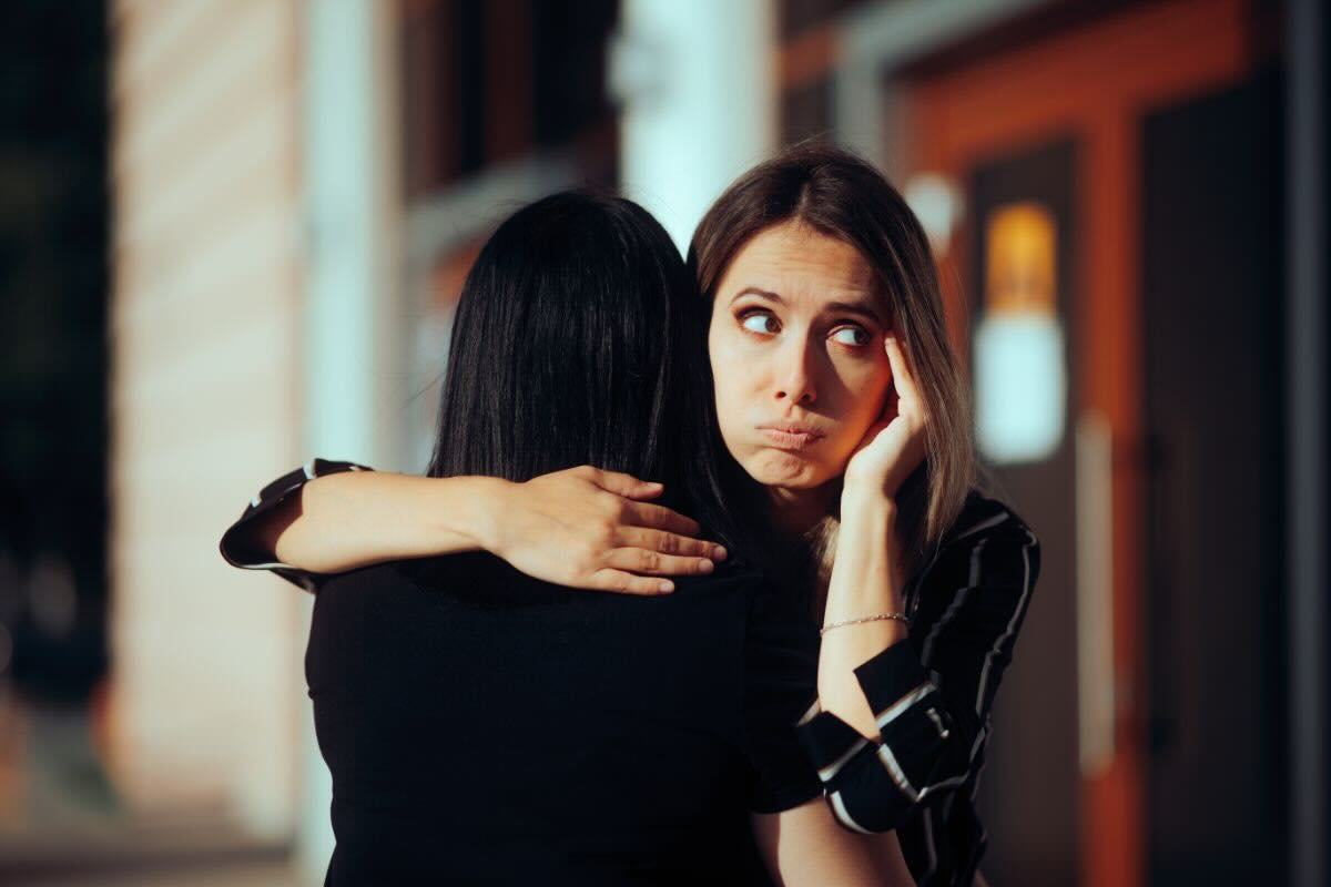 Donna abbraccia un'altra donna ma appare un po' scocciata